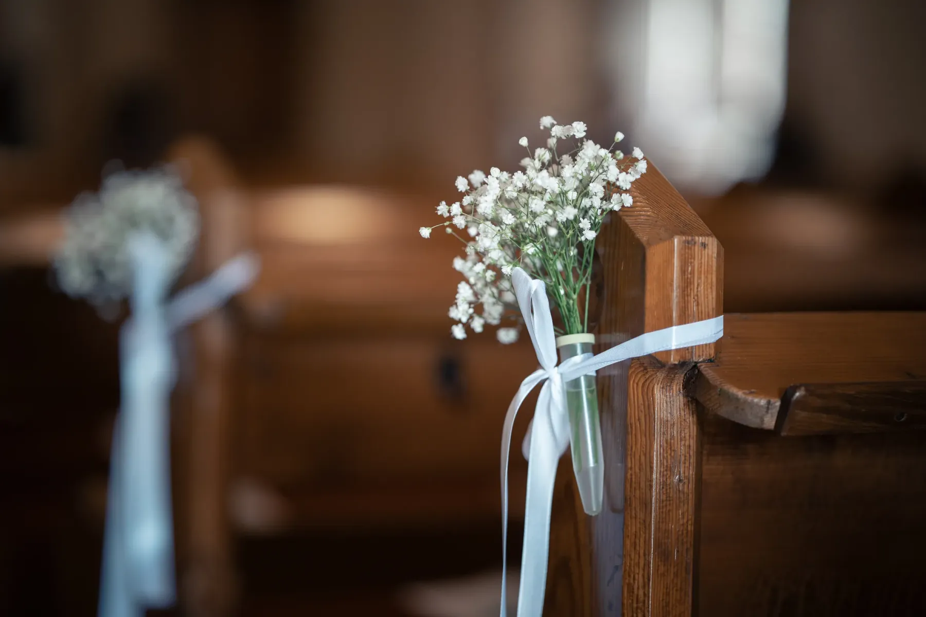 Kirchenbank mit zartem Blumenschmuck vor der Trauung